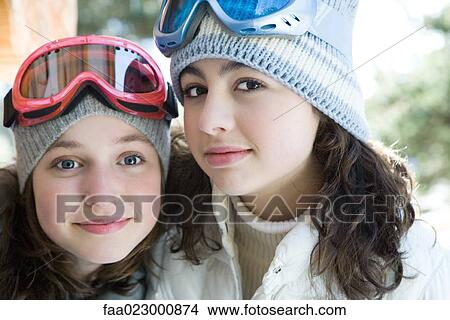 Picture - Two young friends wearing knit hats and ski goggles, smiling at camera, portrait. Fotosearch