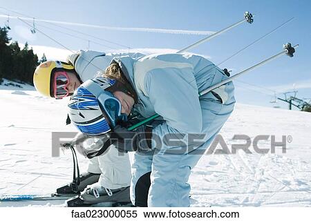 Two young skiers bending over, looking at camera, side view View Large Photo Image Stock Photography - Two young skiers bending over, looking at camera, side view. Fotosearch
