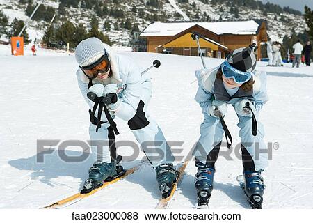 Stock Photo - Two young skiers crouching together, looking at camera. Fotosearch