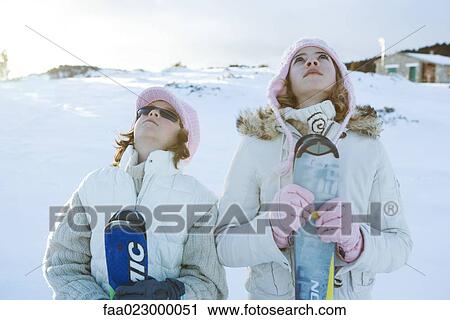 Two young skiers standing together, looking up View Large Photo Image Stock Image - Two young skiers standing together, looking up. Fotosearch