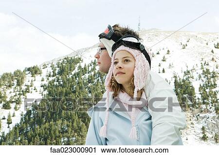 Two young skiers standing together, looking away, one's arm around the other's shoulder View Large Photo Image Stock Image - Two young skiers standing together, looking away, one's arm around the other's shoulder. Fotosearch