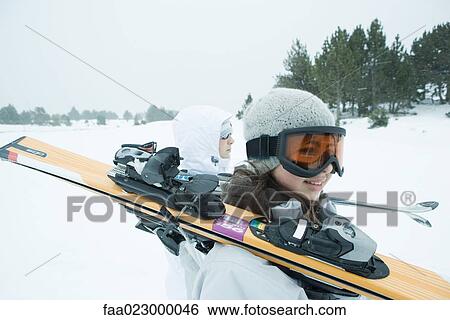 Two young skiers walking together, carrying skis on shoulders View Large Photo Image Stock Photograph - Two young skiers walking together, carrying skis on shoulders. Fotosearch