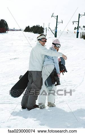 Two young snowboarders walking together, looking over shoulders at camera View Large Photo Image Picture - Two young snowboarders walking together, looking over shoulders at camera. Fotosearch