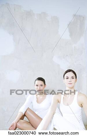Stock Image - Two young women doing yoga pose, one looking at camera. Fotosearch