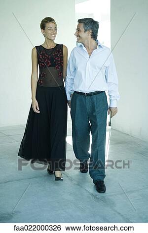 Well-dressed couple walking into room, smiling at each other, full length portrait View Large Photo Image Stock Photograph - Well-dressed couple walking into room, smiling at each other, full length portrait. Fotosearch