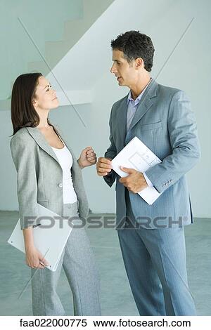 Well dressed man and woman standing in bare home interior, speaking, woman holding binder, man holding blueprints View Large Photo Image Stock Photography - Well dressed man and woman standing in bare home interior, speaking, woman holding binder, man holding blueprints. Fotosearch