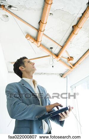 Well-dressed man using laptop, inspecting unfinished home interior View Large Photo Image Stock Photo - Well-dressed man using laptop, inspecting unfinished home interior. Fotosearch