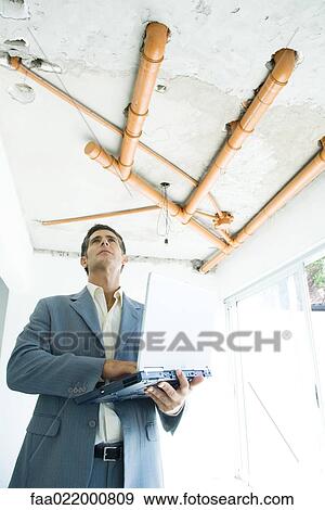 Well-dressed man using laptop, inspecting unfinished home interior View Large Photo Image Stock Photo - Well-dressed man using laptop, inspecting unfinished home interior. Fotosearch