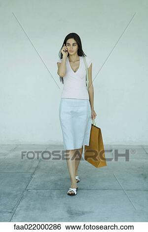 Woman carrying shopping bags, using cell phone, full length portrait View Large Photo Image Stock Photograph - Woman carrying shopping bags, using cell phone, full length portrait. Fotosearch