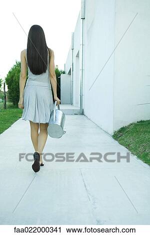 Woman carrying watering can, rear view, full length View Large Photo Image Stock Image - Woman carrying watering can, rear view, full length. Fotosearch