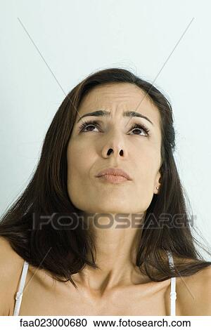 Stock Image - Woman cringing, looking up, portrait. Fotosearch