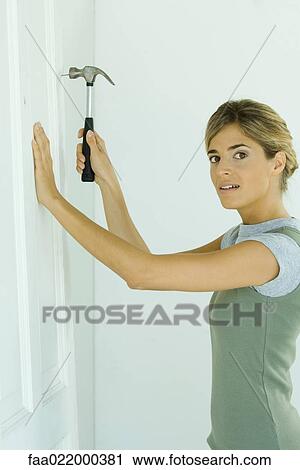 Woman hammering nail into door View Large Photo Image Stock Image - Woman hammering nail into door. Fotosearch
