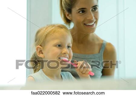 Woman helping little girl brush teeth View Large Photo Image Stock Image - Woman helping little girl brush teeth. Fotosearch