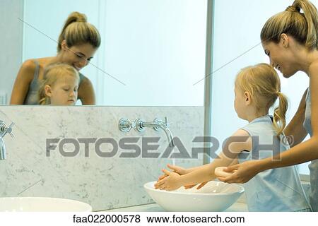 Woman helping little girl wash hands in bathroom sink View Large Photo Image Stock Photo - Woman helping little girl wash hands in bathroom sink. Fotosearch