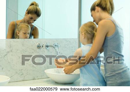 Woman helping little girl wash hands in bathroom sink View Large Photo Image Stock Photo - Woman helping little girl wash hands in bathroom sink. Fotosearch