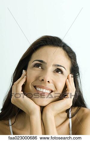 Woman holding face between hands, smiling, looking up, portrait View Large Photo Image Stock Photograph - Woman holding face between hands, smiling, looking up, portrait. Fotosearch
