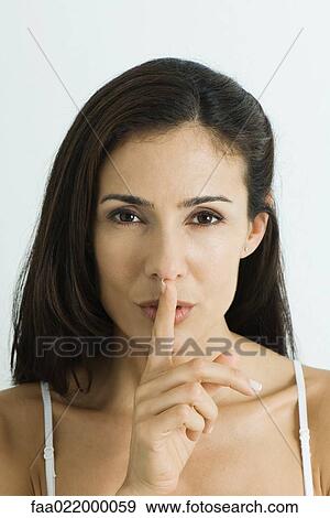 Woman holding finger over lips, looking at camera, portrait View Large Photo Image Stock Photo - Woman holding finger over lips, looking at camera, portrait. Fotosearch