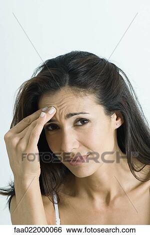 Stock Photograph - Woman holding head, looking at camera, portrait. Fotosearch