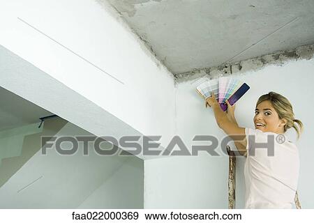 Woman holding up color swatches, looking over shoulder, smiling at camera View Large Photo Image Stock Photo - Woman holding up color swatches, looking over shoulder, smiling at camera. Fotosearch