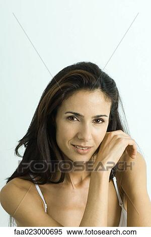 Stock Photography - Woman looking at camera, touching cheek with back of hand, portrait. Fotosearch