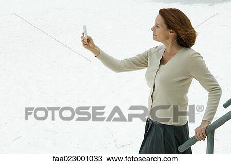 Woman looking at cell phone, arm outstretched, side view View Large Photo Image Stock Image - Woman looking at cell phone, arm outstretched, side view. Fotosearch