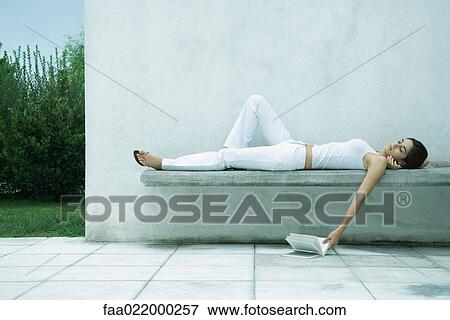 Woman lying on back, letting book fall to ground View Large Photo Image Stock Photo - Woman lying on back, letting book fall to ground. Fotosearch
