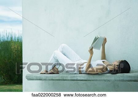 Woman lying on back, reading book View Large Photo Image Stock Photo - Woman lying on back, reading book. Fotosearch