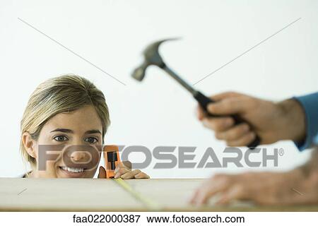 Woman measuring board while man hammers, focus on woman in background View Large Photo Image Stock Photo - Woman measuring board while man hammers, focus on woman in background. Fotosearch