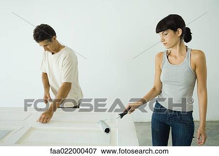 Woman painting door with paint roller, man protecting woodwork with masking tape View Large Photo Image Stock Photo - Woman painting door with paint roller, man protecting woodwork with masking tape. Fotosearch