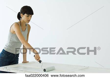 Stock Photograph - Woman painting door with paint roller. Fotosearch