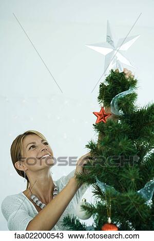 Woman placing star on top of Christmas tree View Large Photo Image Stock Image - Woman placing star on top of Christmas tree. Fotosearch