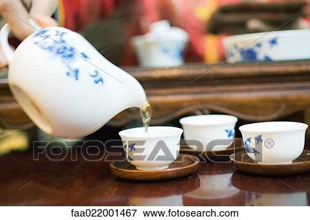 Stock Photo - Woman pouring tea, cropped view. Fotosearch