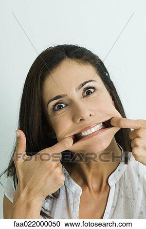 Woman pulling sides of mouth, looking at camera, portrait View Large Photo Image Stock Image - Woman pulling sides of mouth, looking at camera, portrait. Fotosearch