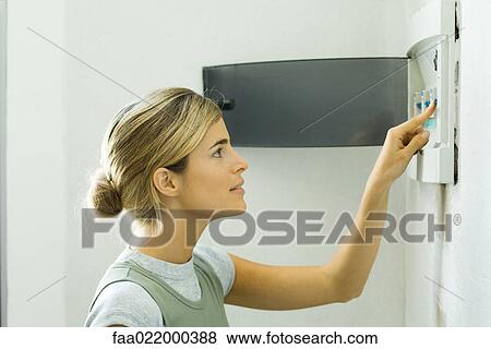 Stock Photo - Woman pushing lever in fuse box. Fotosearch