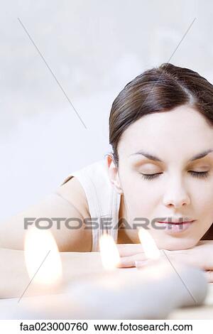 Woman reclining next to burning candles, head resting on arms, eyes closed View Large Photo Image Stock Image - Woman reclining next to burning candles, head resting on arms, eyes closed. Fotosearch