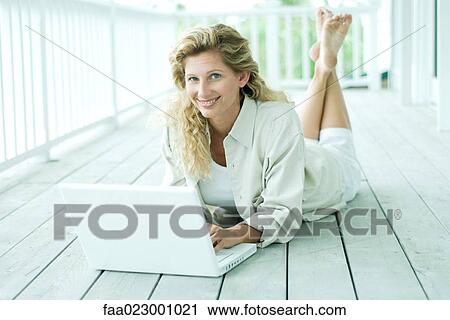 Woman reclining on porch, using laptop computer, smiling at camera, portrait View Large Photo Image Stock Image - Woman reclining on porch, using laptop computer, smiling at camera, portrait. Fotosearch