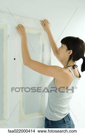 Woman removing masking tape from freshly painted woodwork on door View Large Photo Image Picture - Woman removing masking tape from freshly painted woodwork on door. Fotosearch