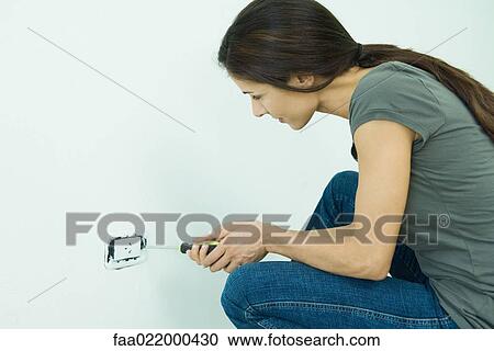 Stock Image - Woman replacing outlet cover. Fotosearch