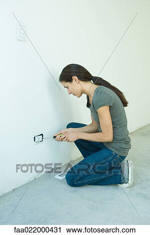 Stock Image - Woman replacing outlet cover. Fotosearch