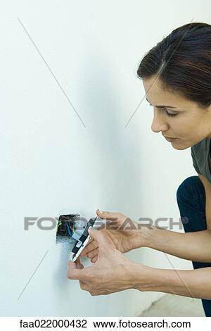 Stock Image - Woman replacing outlet cover. Fotosearch