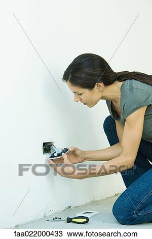Stock Image - Woman replacing outlet cover. Fotosearch