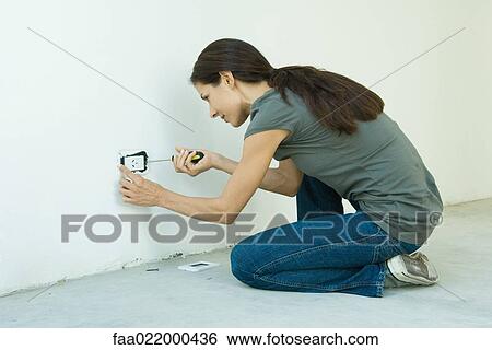 Stock Photograph - Woman replacing outlet cover. Fotosearch