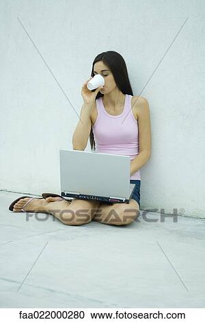Woman sitting on ground, using laptop and drinking from disposable cup, full length View Large Photo Image Stock Image - Woman sitting on ground, using laptop and drinking from disposable cup, full length. Fotosearch