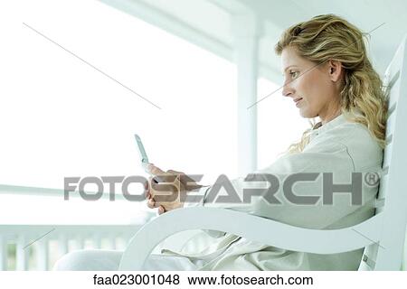 Woman sitting on porch, looking at cell phone, profile View Large Photo Image Stock Photo - Woman sitting on porch, looking at cell phone, profile. Fotosearch