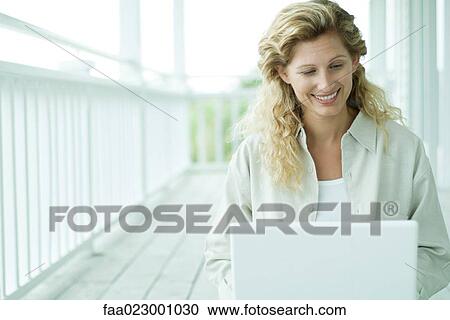 Woman sitting on porch using laptop computer, smiling, waist up View Large Photo Image Stock Image - Woman sitting on porch using laptop computer, smiling, waist up. Fotosearch