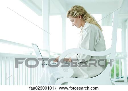Woman sitting on porch, using laptop computer, smiling View Large Photo Image Stock Photo - Woman sitting on porch, using laptop computer, smiling. Fotosearch