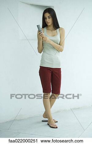 Woman standing dialing cell phone, full length portrait View Large Photo Image Stock Image - Woman standing dialing cell phone, full length portrait. Fotosearch