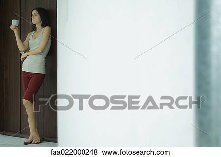 Woman standing holding cup, full length portrait View Large Photo Image Stock Photo - Woman standing holding cup, full length portrait. Fotosearch