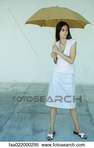 Woman standing under umbrella, full length portrait View Large Photo Image Stock Photography - Woman standing under umbrella, full length portrait. Fotosearch