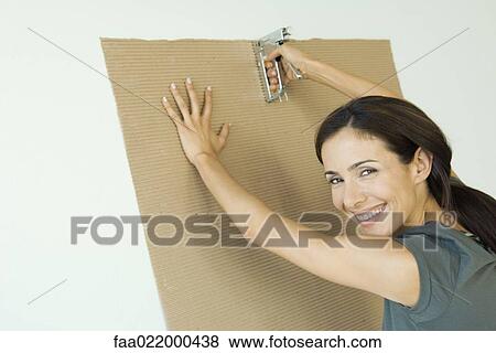 Woman stapling corrugated cardboard to wall View Large Photo Image Stock Photo - Woman stapling corrugated cardboard to wall. Fotosearch